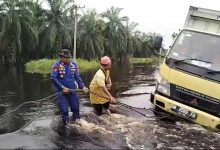 Dua Perwira Bantu Tarik Mobil Box Terperosok di Lokasi Banjir Pelalawan