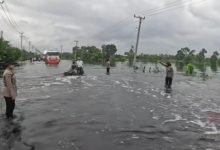 Dua Polwan personel Polres Pelalawan mengatur arus lalu lintas di Jalintim KM 83 yang digenangi banjir.