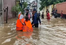 Petugas DPKP Kota Depok membantu mengarahkan siswa terjebak banjir usai pulang sekolah di wilayah Pancoran Mas, Depok. (Istimewa)